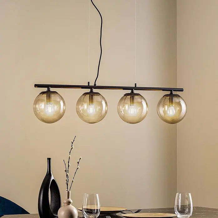 Lucande Pendelleuchte Sotiana - L x B x H: 96 x 18 x 18 cm, alu / grau / zink, rauchgrau, Schwarz, E14 - Lineare Pendelleuchte mit schwarzem Metallrahmen und vier bernsteinfarbenen Glaskugelschirmen, über einem Esstisch.