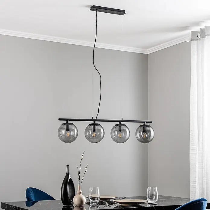 Lucande Pendelleuchte Sotiana - L x B x H: 96 x 18 x 18 cm, alu / grau / zink, rauchgrau, Schwarz, E14 - Schwarze Pendelleuchte mit vier Rauchglas-Kugeln, über einem Esstisch hängend.