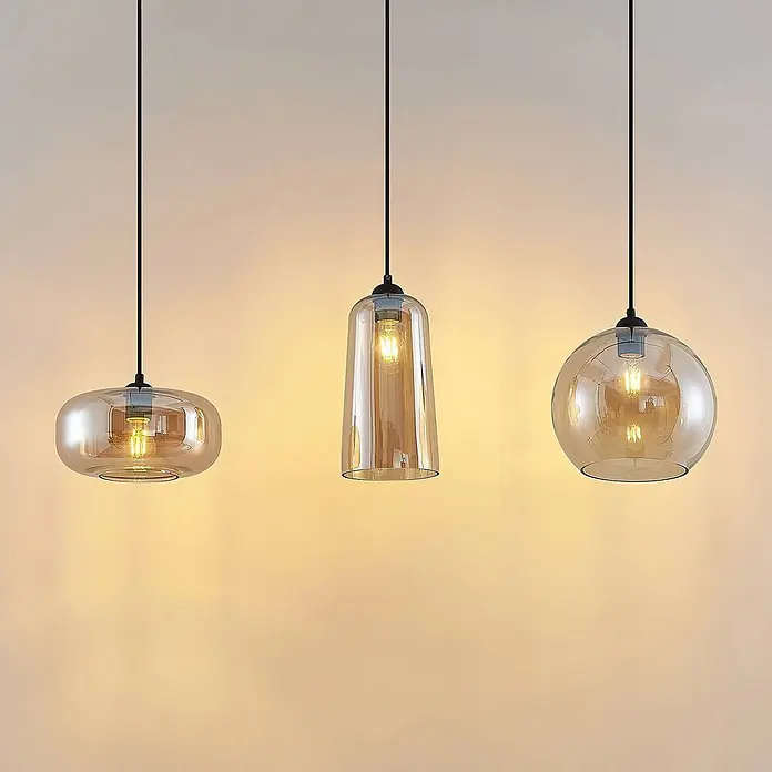 Lucande Pendelleuchte Wilja - creme / amber, Schwarz, amber, E27 - Dreier-Set bernsteinfarbener Glas-Pendelleuchten in verschiedenen Formen mit sichtbaren Glühbirnen, an schwarzen Kabeln.
