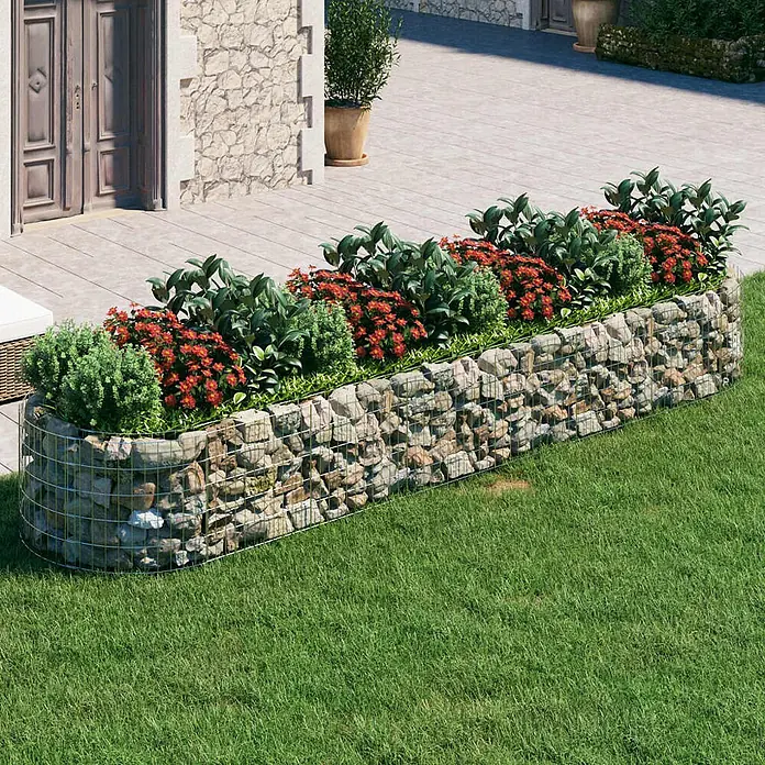 Furnicato Gabionen-Hochbeet - 100 x 400 x 50 cm, Metall, Fassungsvermögen Erde: 2.000 g - Gabionen-Hochbeet aus Metallgitter und Natursteinen, bepflanzt mit roten Blumen und grünem Laub, trennt Terrasse vom Rasen.