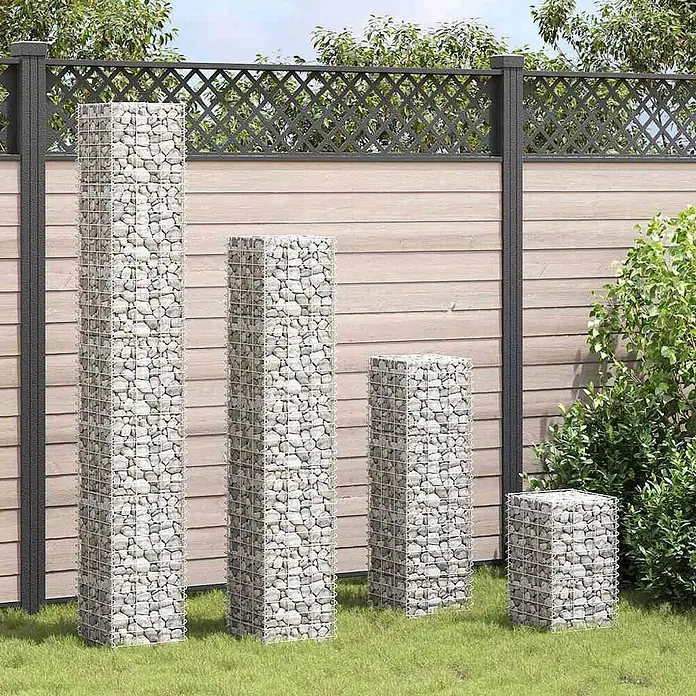 Furnicato Gabionen-Hochbeet - 30 x 30 x 200 cm, Metall, Fassungsvermögen Erde: 1.200 g - Vier unterschiedlich hohe Gabionensäulen, gefüllt mit hellen Steinen, auf Rasen neben einem Gartenzaun.