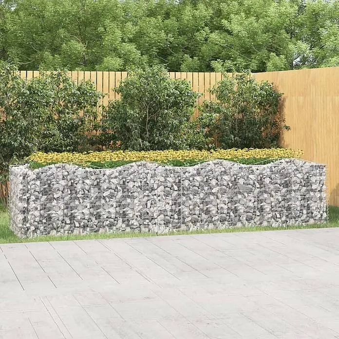 Furnicato Gabionen-Hochbeet - 100 x 400 x 100 cm, Metall, Fassungsvermögen Erde: 4.000 g - Großes Gabionen-Hochbeet aus grauen Steinen und Metallgitter, mit gewelltem Rand und gelben Blumen, im Garten platziert.