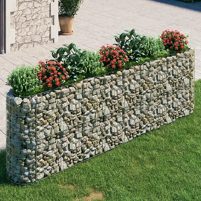 Furnicato Gabionen-Hochbeet - 50 x 330 x 100 cm, Metall, Fassungsvermögen Erde: 1.650 g - Langes Gabionen-Pflanzgefäß aus Drahtgitter mit Steinfüllung, bepflanzt mit grünen und rot blühenden Pflanzen im Garten.