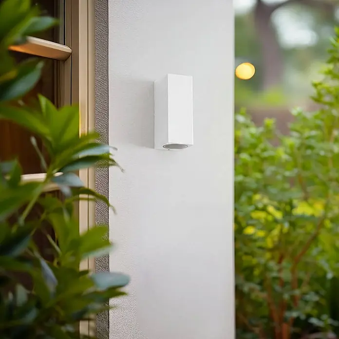Lucande Außenwandleuchte Xava - weiß / opal, IP65 - Weißes, rechteckiges Wandlicht für den Außenbereich an einer strukturierten Fassade montiert.