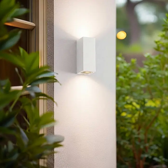 Lucande Außenwandleuchte Xava - weiß / opal, IP65 - Weiße rechteckige Außenwandleuchte, die eine strukturierte Wand nach oben und unten beleuchtet.