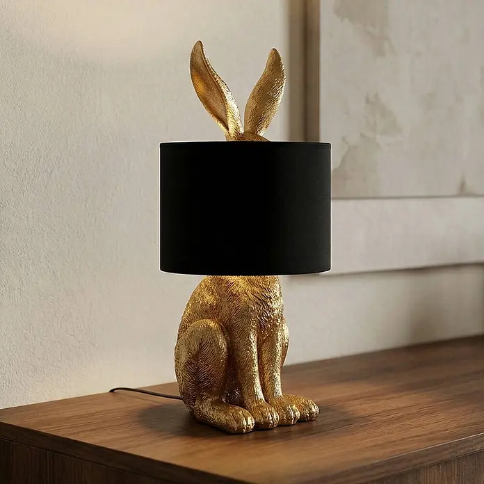 Lindby Tischleuchte Lorentina - L x B x H: 24 x 24 x 57 cm, messing / gold, schwarz, E27 - Goldene Hasen-Tischlampe mit schwarzem Schirm auf Holzoberfläche.