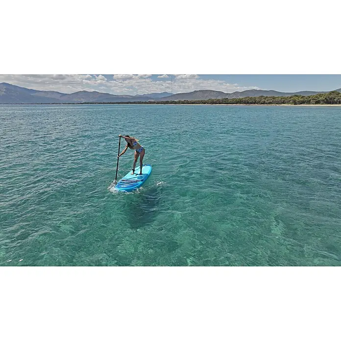 Aqua Marina SUP-Board-Set Vapor - L x B x H: 315 x 79 x 15 cm, Blau, Tragkraft: 140 kg - Eine Frau paddelt auf einem blauen Board im klaren, türkisfarbenen Meer vor Bergen.