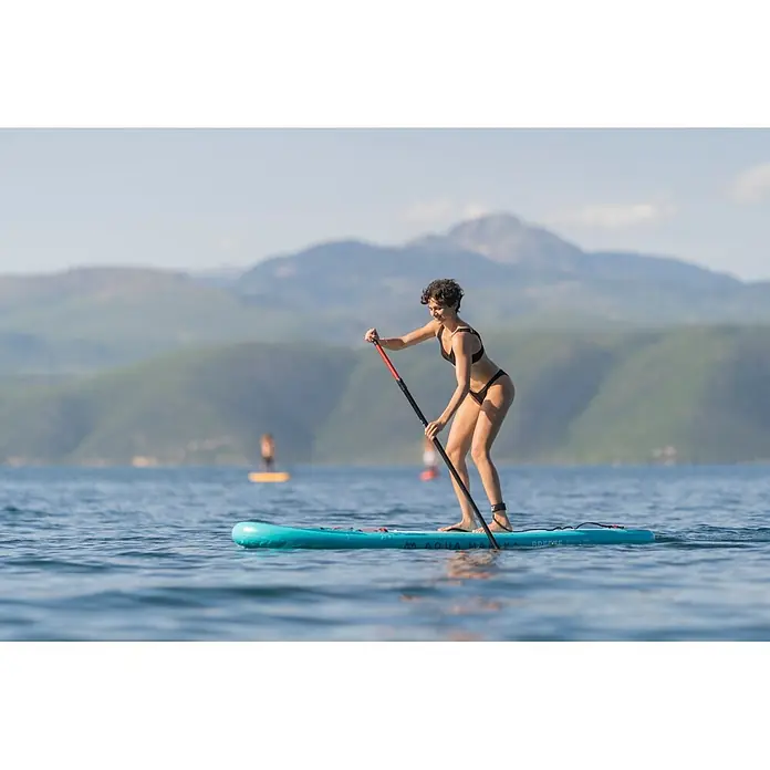 Aqua Marina SUP-Board-Set Vapor - L x B x H: 315 x 79 x 15 cm, Blau, Tragkraft: 140 kg - Frau auf einem türkisen aufblasbaren Stand-Up-Paddleboard, paddelnd auf einem See.