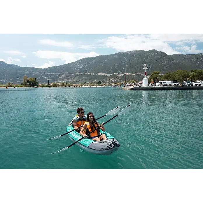 Aqua Marina Kajak Laxo 10'6" - L x B: 320 x 90 cm, Geeignet für: 2 Personen, Tragkraft: 180 kg - Zwei Personen in einem aufblasbaren Kajak in Türkis und Grau auf dem Wasser, vor einer malerischen Küste und Bergen.