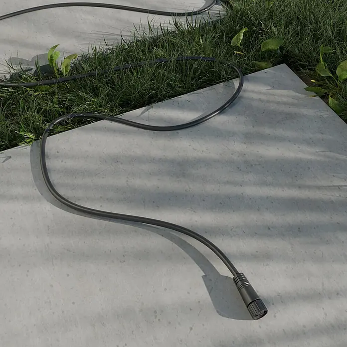 Steinel Verlängerungskabel 24V-Garten-Lichtsystems - IP67, 1 m - Schwarzes Kabel mit Stecker auf Betonplatten und grünem Gras.