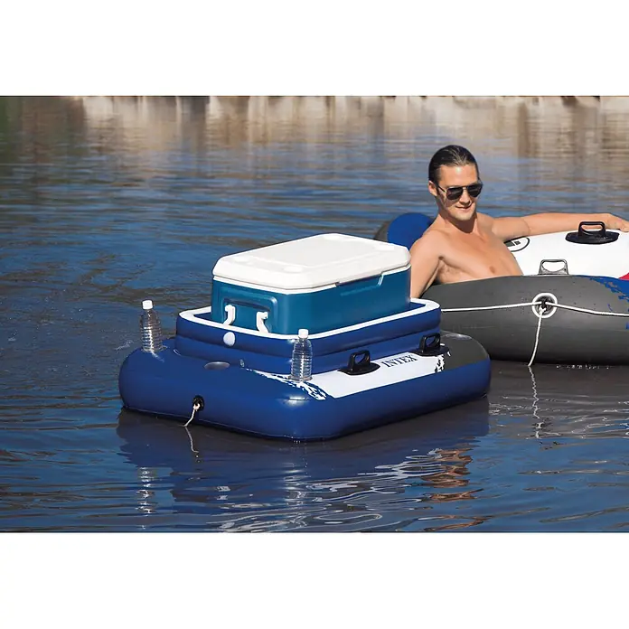 Intex Kühlbox Mega Chill 2 - Grau, Weiß, Blau, L x B x H: 114 x 86 x 42 cm - Blaues aufblasbares Kühlbox-Floß mit blauer und weißer Kühlbox und zwei Wasserflaschen, auf dem Wasser schwimmend neben einer Person.