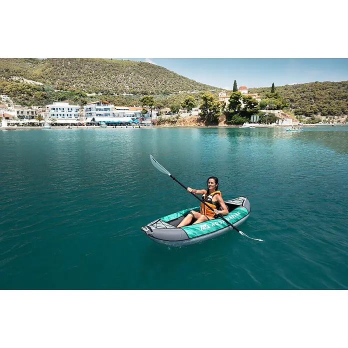 Aqua Marina Kajak Laxo 9'4" - L x B: 285 x 90 cm, Geeignet für: 1 Person, Tragkraft: 110 kg - Frau paddelt ein grau-grünes Aqua Marina aufblasbares Kajak auf blauem Wasser.