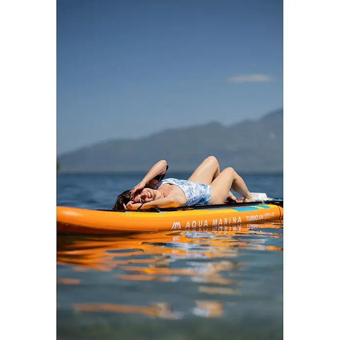 Aqua Marina SUP-Board-Set Turbo 330 - L x B x H: 320 x 81 x 15 cm, Mehrfarbig, Tragkraft: 140 kg - Frau entspannt auf einem orangefarbenen Aqua Marina Turbo 330 Paddleboard im Wasser.