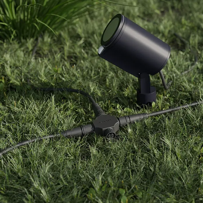 Steinel X-Verbinder Cross-Road 24V Garten-Lichtsystem - Schwarz - Schwarzer Outdoor-Spotlight und Kabelverteiler im grünen Gras für Gartenbeleuchtung.
