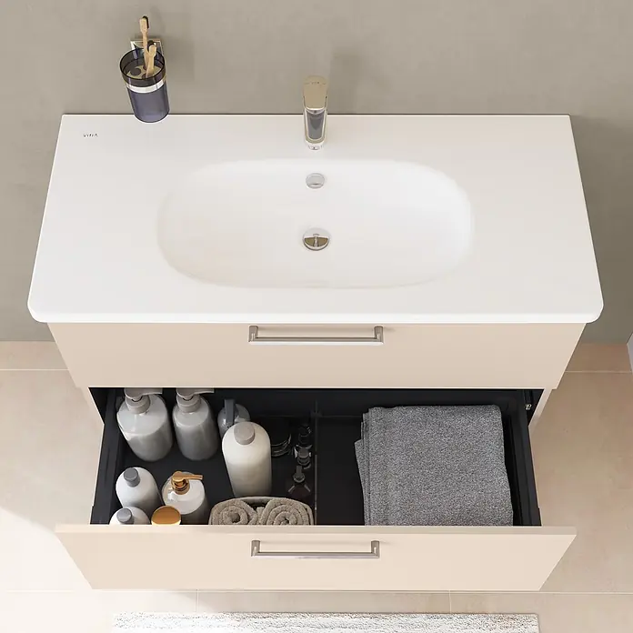 VitrA Badmöbel-Set Root Flat - B x T x H: 80 x 45 x 65 cm, Sahara Beige, Hochglänzend - Beiger Waschtischunterschrank mit weißem Waschtisch, Chromgriffen. Untere Schublade offen, zeigt Pflegeprodukte und Handtücher.