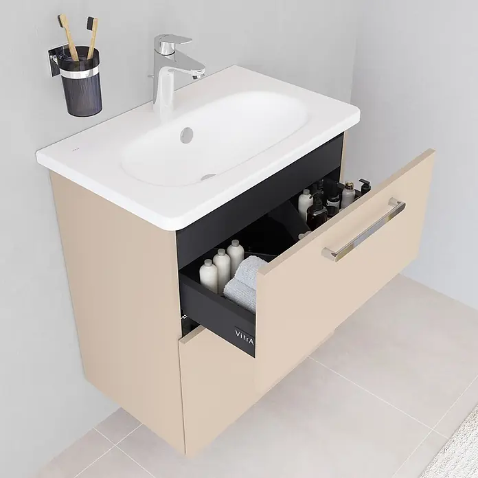 VitrA Root Flat Compact Badmöbel-Set Compact - B x T x H: 60 x 37 x 65 cm, Sahara Beige, Hochglänzend - Beigefarbener Badschrank mit weißem Waschbecken. Offene Schublade zeigt dunkles Inneres mit Pflegeprodukten. Chromarmatur, Zahnbürsten im Wandhalter.