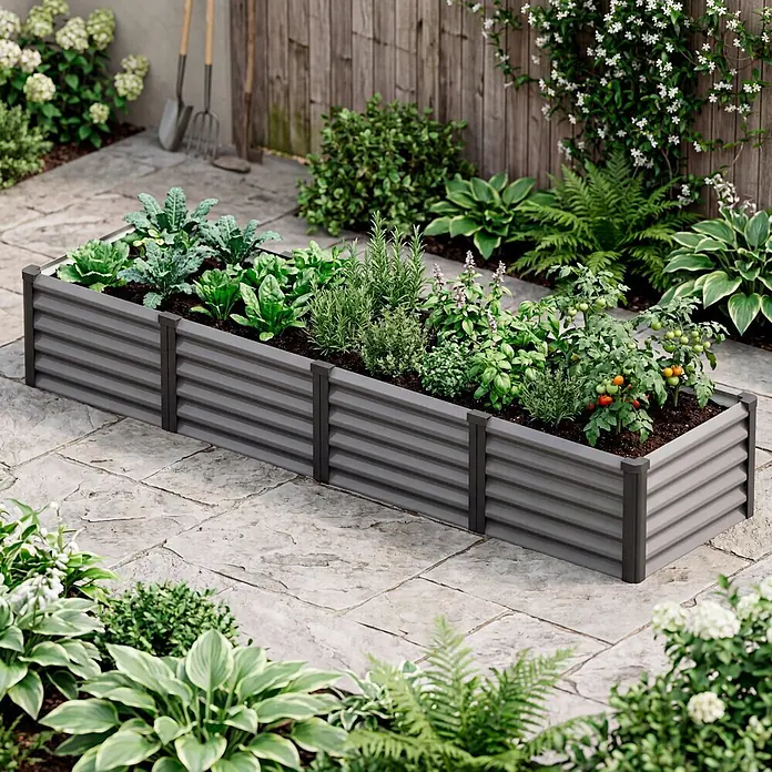 Vitavia Hochbeet Meta In&Out 401 - 245 x 65 x 40 cm, Zincalume®, Granit/Schwarz - Ein langes, dunkelgraues Hochbeet aus Wellblech, gefüllt mit verschiedenen Grünpflanzen, Kräutern und kleinen Tomaten, auf einer Steinterrasse.