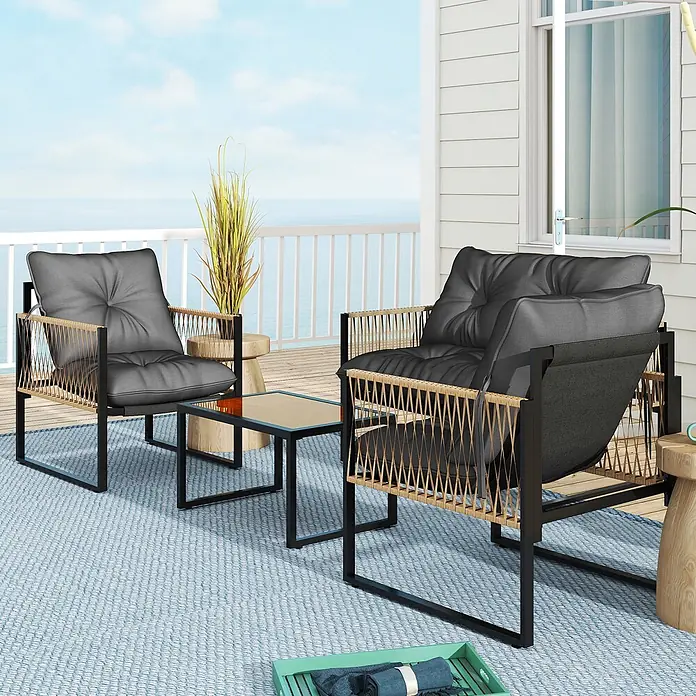Outsunny Loungemöbel-Set - 4 -tlg., PE-Rattan, Polyester, 2x Stuhl, 1x Sofa, 1x Tisch, 3x Sitzkissen, Dunkelgrau - Zwei Outdoor-Stühle mit schwarzen Gestellen, naturfarbenen geflochtenen Seiten und grauen Kissen, neben einem Glastisch auf einer Terrasse am Meer.