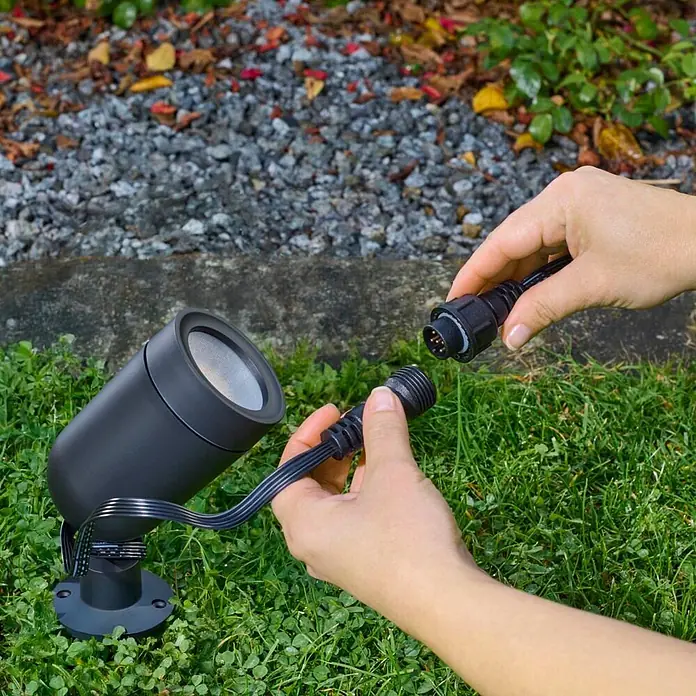 Hama LED-Gartenstrahler WLAN Gartenstecker - Schwarz - Hände verbinden den schwarzen Stromanschluss eines Außenstrahlers.