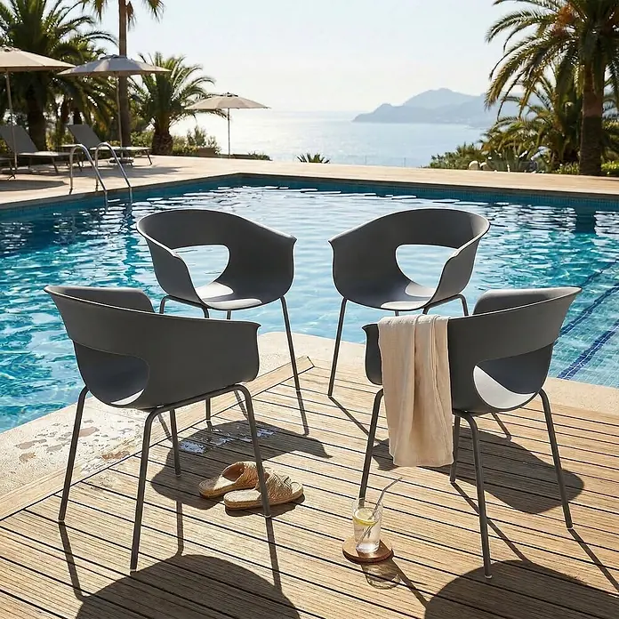Outsunny Gartenstuhl-Set - 4 Stk., Metall, Kunststoff, Dunkelgrau - Vier graue Outdoor-Stühle mit ausgeschnittenen Rückenlehnen auf einem Holzdeck am Pool, mit Meerblick.
