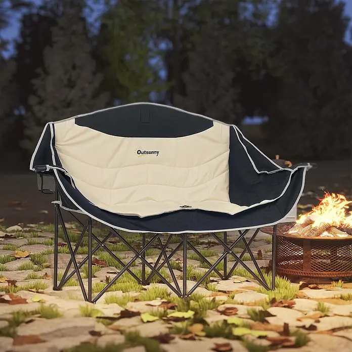 Outsunny Campingstuhl - 210g/m² 600D Oxford-Gewebe, Metall, Klappbar, Khaki - Ein cremefarbener und schwarzer gepolsterter Zweisitzer-Campingstuhl steht abends draußen an einem Lagerfeuer.