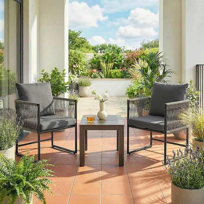Outsunny Gartenstuhl-Set - 2 Stk., Stahl, PE-Rattan, Dunkelgrau - Dunkelgraue Outdoor-Stühle mit geflochtenen Details und passendem Tisch auf sonniger Terrasse mit Pflanzen.