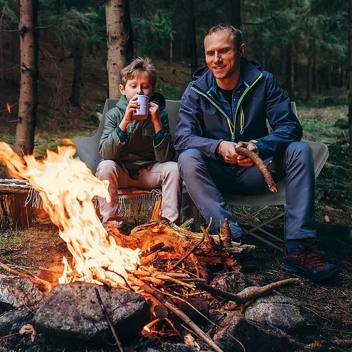 Outsunny Campingstuhl - Baumwolle, pulverbeschichtetes Metall, 600D Oxford-PE-Gewebe, Klappbar, Grau - Zwei Personen sitzen auf einem grauen Campingstuhl am Lagerfeuer im Wald.