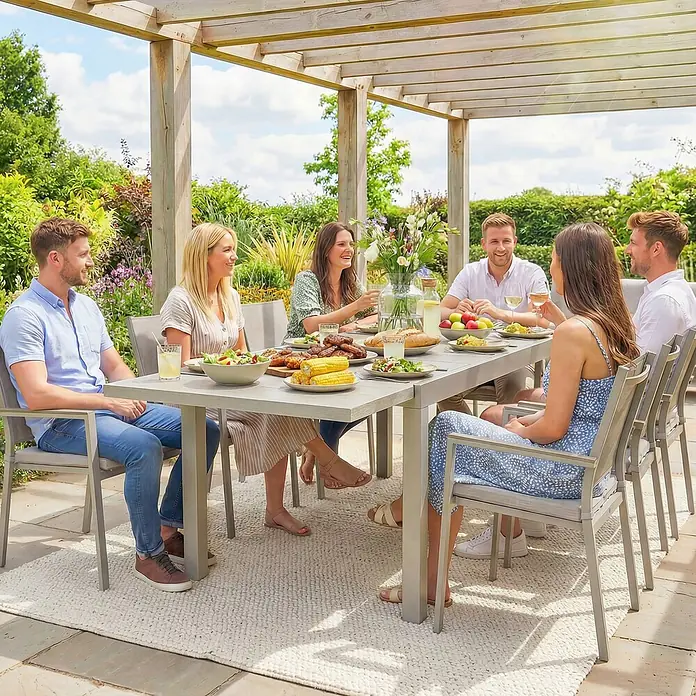 Outsunny Gartentisch - L x B x H: 214 x 85 x 75 cm, Aluminium, Stahl, Hellgrau - Eine hellgraue Essgruppe für den Außenbereich und ein texturierter cremefarbener Teppich, genutzt von sechs Personen beim Essen unter einer Holzpergola.