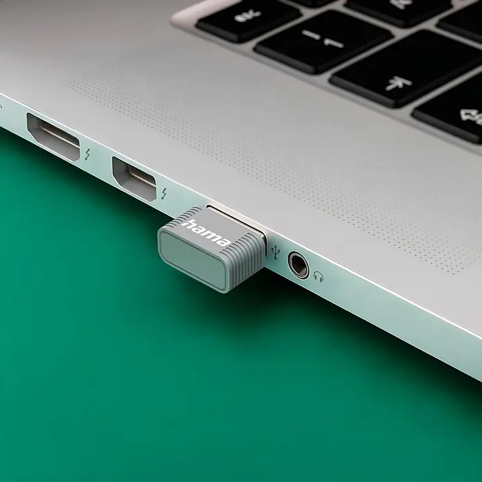 Hama USB-Stick 00053315 AX900 Nano-WLAN-USB-Stick 2.4/5 GHz - Silber - Grauer Hama USB-Adapter in einen silbernen Laptop gesteckt, neben anderen Anschlüssen.