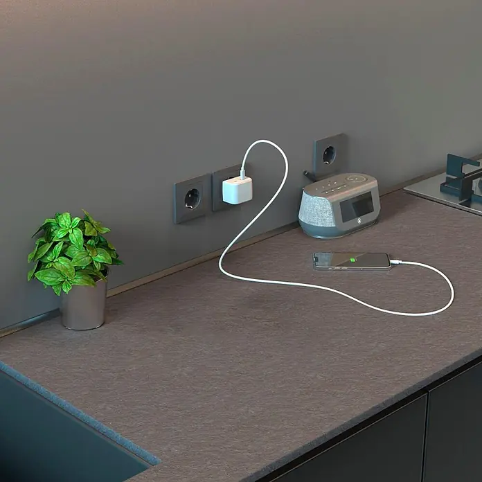 Hama Steckdosenleiste 223191 mit USB-C Adapter 5-fach - Weiß - Smartphone lädt auf dunkler Küchenarbeitsplatte an einer Wandsteckdose.