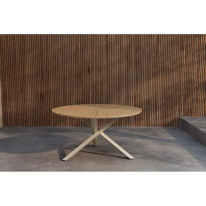 Ebuy24 Gartentisch rund New Mexico - Ø x H: 140 x 75 cm, Teak, Natur, Stapelbar - Runder Outdoor-Esstisch mit lattenförmiger Holzplatte und hellem X-förmigem Gestell auf einer Terrasse.