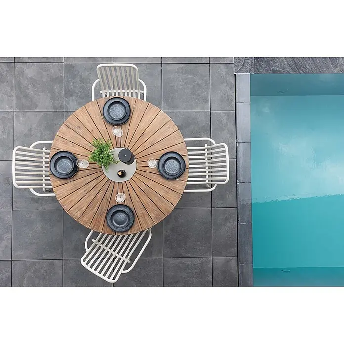 Ebuy24 Gartentisch rund Rosario - Ø x H: 140 x 75 cm, Akazie, Braun, Stapelbar - Gartenessgruppe mit rundem Holztisch und vier hellen Metallstühlen auf Terrasse neben türkisfarbenem Pool.