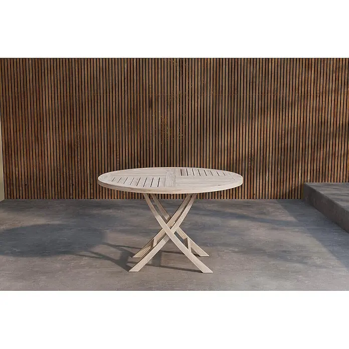 Ebuy24 Gartentisch rund Kenya - Ø x H: 120 x 75 cm, Teak, Whitewash, Stapelbar - Heller runder Holztisch für den Außenbereich mit kreuzförmigem Gestell auf einer Betonterrasse.