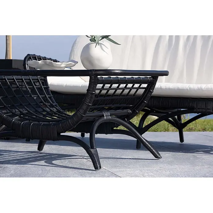 Ebuy24 Garten-Loungetisch Moana - Rattan, Schwarz, Stapelbar, L x B x H: 96 x 60 x 47 cm - Schwarzer Rattan-Loungesessel und Sofa mit weißen Kissen auf einer Terrasse. Ideal für entspanntes Sitzen im Freien.