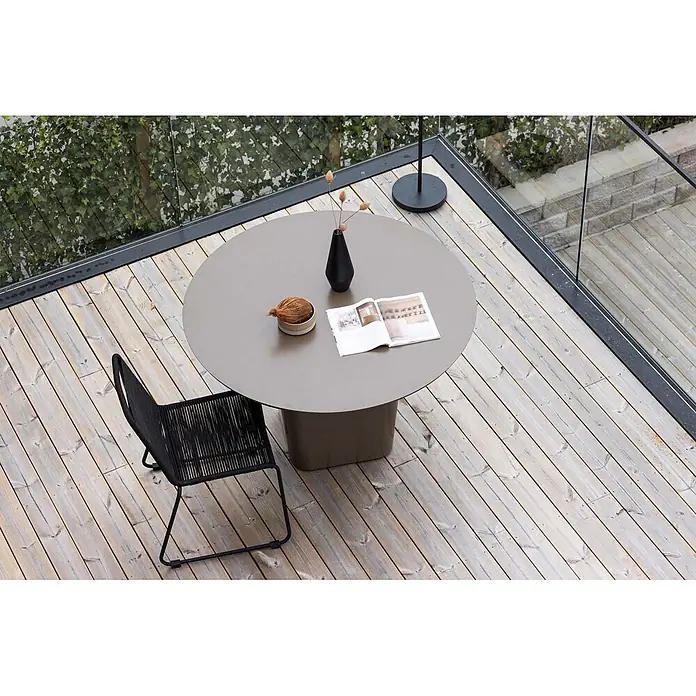 Ebuy24 Gartentisch rund Santa Fe - Ø x H: 120 x 75 cm, Aluminium, Braun, Stapelbar - Runder grauer Outdoor-Tisch und schwarzer geflochtener Stuhl auf Holzterrasse.