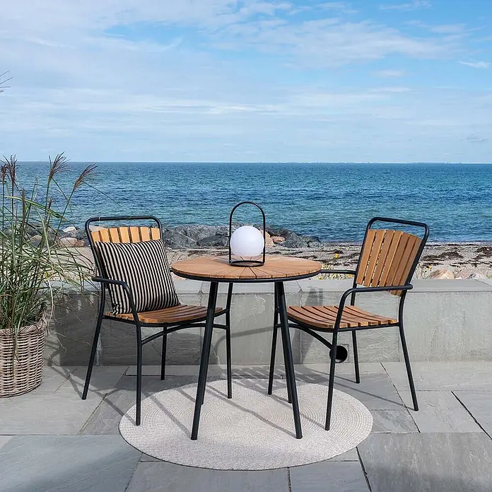 Ebuy24 Gartentisch rund Cleveland - Ø x H: 70 x 74 cm, Teakholz Metall, Teak, Stapelbar - Outdoor-Bistrotisch-Set mit Holzlatten und zwei Stühlen mit schwarzen Metallrahmen.