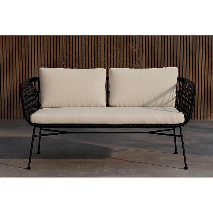 Ebuy24 Loungesofa Isola - B x T x H: 67 x 140 x 71 cm, Stahl., Schwarz - Schwarzes Rattan-Outdoor-Zweisitzer-Sofa mit cremefarbenen Kissen auf einer Terrasse.