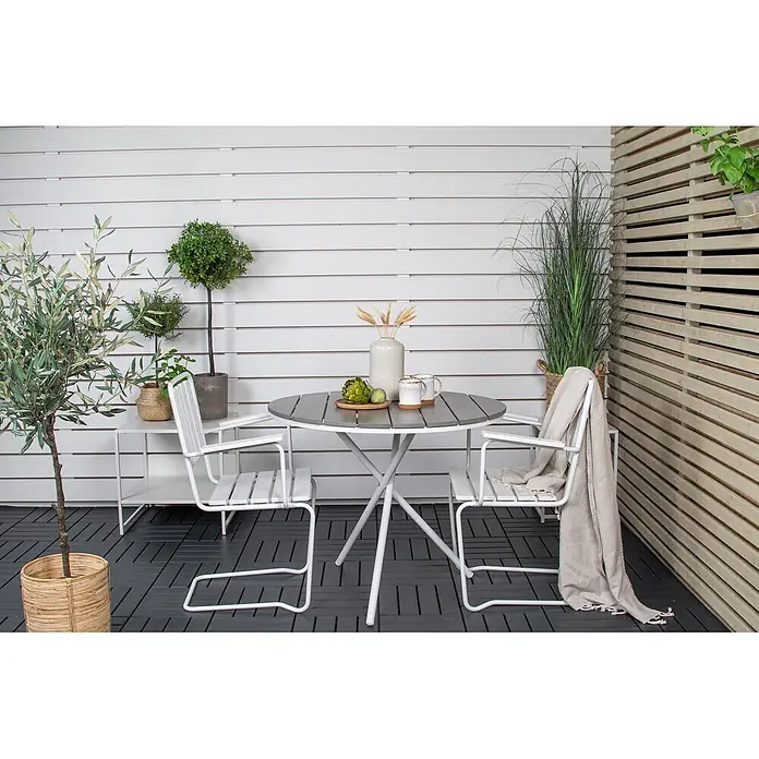 Ebuy24 Gartentisch rund Parma - Ø x H: 90 x 74 cm, Aintwood, Aluminium, Grau, Stapelbar - Runder grauer Gartentisch und zwei weiße Metallstühle auf einem modernen Balkon.