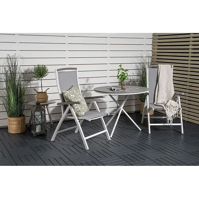 Ebuy24 Gartentisch rund Parma - Ø x H: 90 x 74 cm, Aintwood, Aluminium, Grau, Stapelbar - Zwei grau-weiße klappbare Gartenstühle und ein passender runder Klapptisch auf einem gefliesten Außenboden.