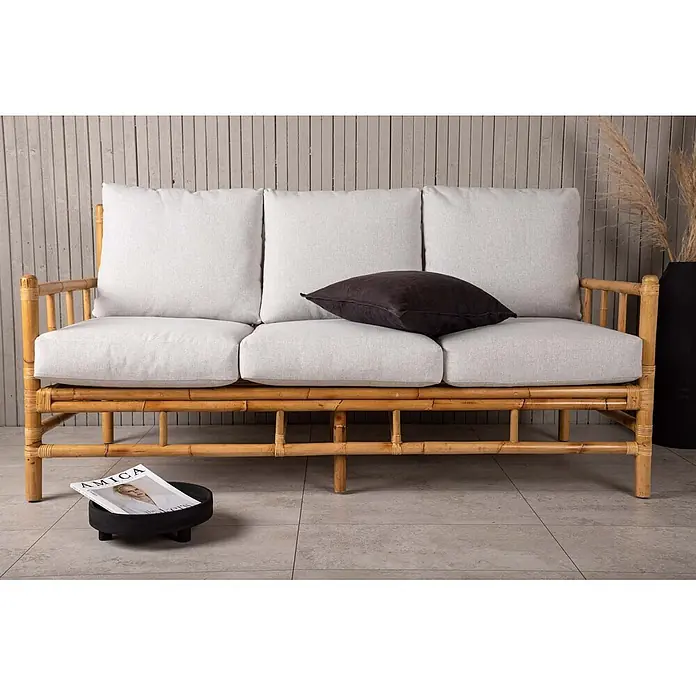 Ebuy24 Loungesofa Cane - B x T x H: 77 x 180 x 88 cm, Rattan., Natur - Ein helles Bambus-Dreisitzer-Sofa mit hellgrauen Kissen und einem dunklen Zierkissen, auf Fliesenboden.
