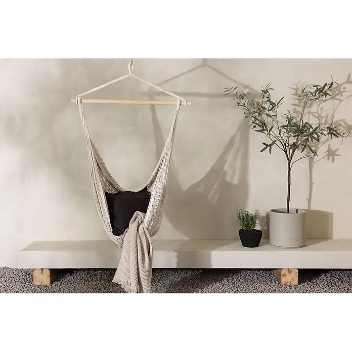 Ebuy24 Hängesessel Kalino - Textil, Ecru - Ein heller Makramee-Hängesessel mit schwarzem Kissen und beigem Überwurf in einem Innen-/Außenbereich.