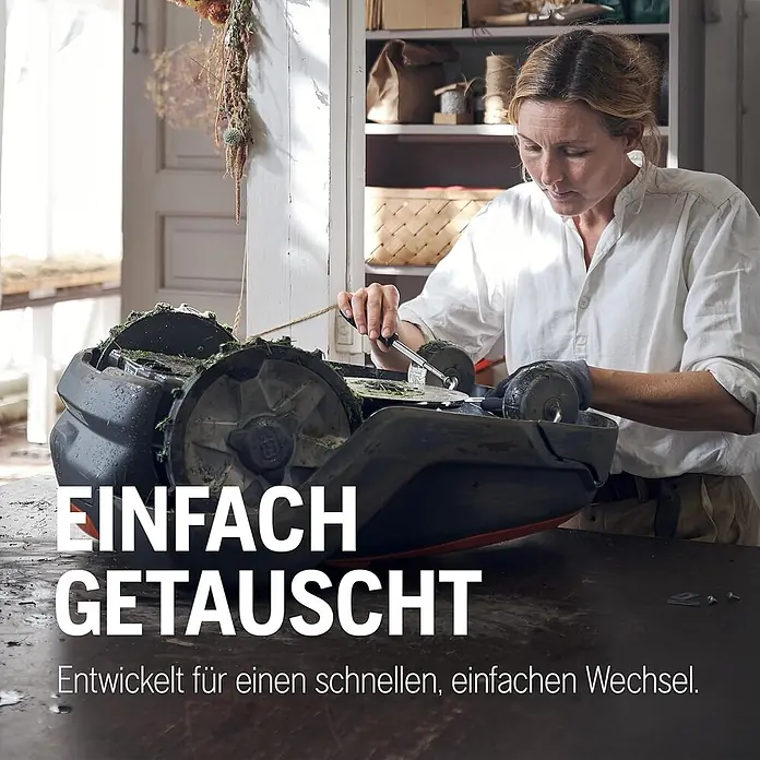 Husqvarna Ersatzmesser-Set für Mähroboter Endurance Messer 6er-Pack - Passend für: alle Husqvarna Automower Modelle, 6 Stk. - Frau wartet einen dunklen Mähroboter, der für schnellen und einfachen Teiletausch konzipiert ist.