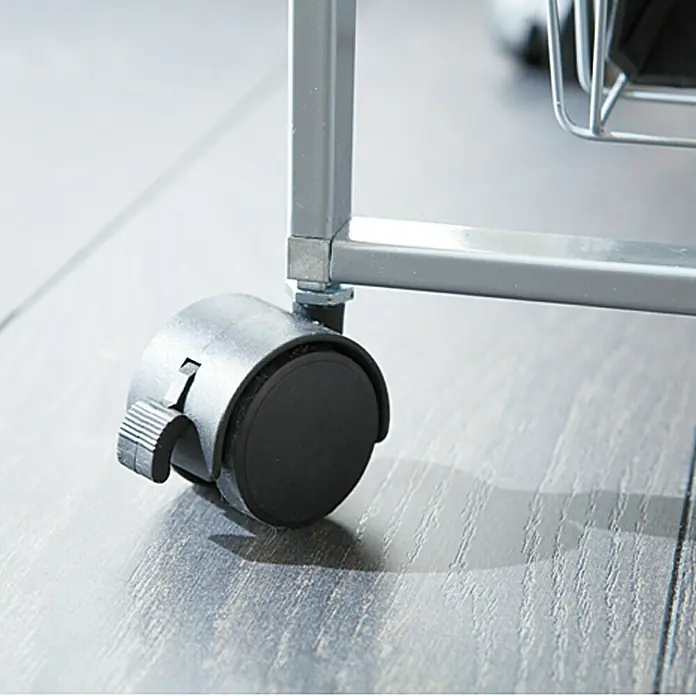 Regalux Clever Set de ruedas - 4 ud. - Primer plano de un carro rodante gris con una rueda giratoria con bloqueo negra sobre un piso de madera.