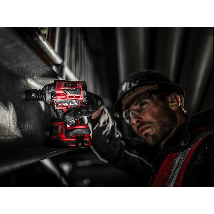 Einhell Professional Power X-Change 18V Akku-Schlagschrauber TP-CW 18/350-C Li BL - Solo - 18 V, Ohne Akku, 350 Nm - Roter und schwarzer Akku-Schlagschrauber mit 20mm Nuss, von einem Arbeiter mit Schutzkleidung verwendet.