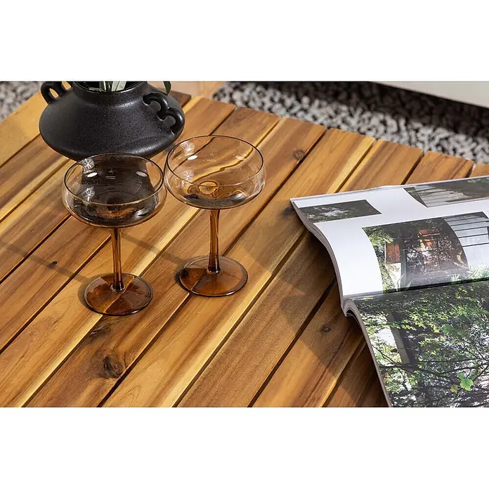 Ebuy24 Garten-Loungetisch Penh - Akazie, Natur, Stapelbar, L x B x H: 100 x 65 x 40 cm - Zwei bernsteinfarbene Coupé-Gläser auf einem Holzlamellentisch.