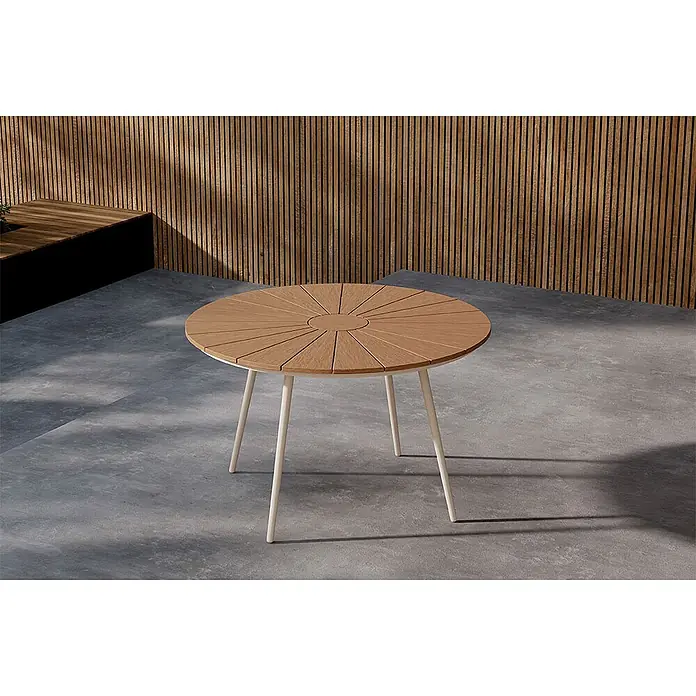 Ebuy24 Gartentisch rund San Vito - Ø x H: 120 x 74 cm, AluminiumSperrholz, Beige, Stapelbar - Runder Outdoor-Tisch mit heller Holzplatte im Sonnenstrahlmuster und cremefarbenen Metallbeinen auf einer Betonterrasse.