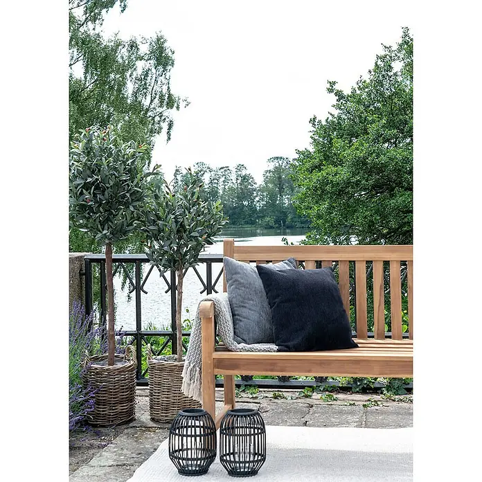 Ebuy24 Gartenbank Cabo - B x T x H: 150 x 150 x 92 cm, Teak., Holz - Zwei schwarze Zierlaternen mit Lattenrost-Design auf einem Outdoor-Terrassenteppich neben einer Holzbank.