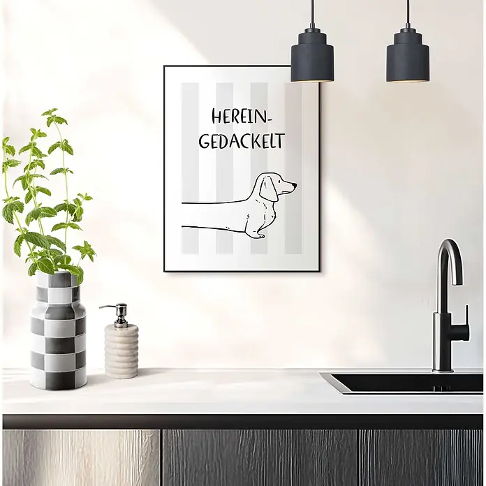 Reinders Bild Slim Frame Black - Herein Gedackelt, B x H: 30 x 40 cm - Gerahmtes Poster mit Dackel-Illustration und Text "HEREIN-GEDACKELT" an Küchenwand über einer Spüle.