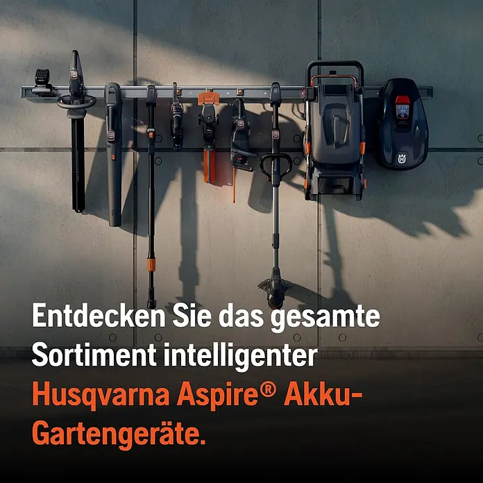 Husqvarna Benzin-Rasenmäher LC247 - 2.200 W, 139 cm³, Schnittbreite: 470 mm - Verschiedene Husqvarna Aspire Akku-Gartengeräte in Schwarz/Orange, ordentlich an einem Wandschienensystem in einer Garage aufgehängt.