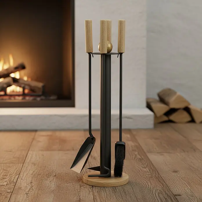Lienbacher Juego de utensilios para chimenea - 4 pzs., Con asas de madera, Antracita, Altura: 64 cm - Juego de herramientas de chimenea moderno con soporte de metal negro, mangos y base de madera clara, bola dorada, junto a una chimenea.
